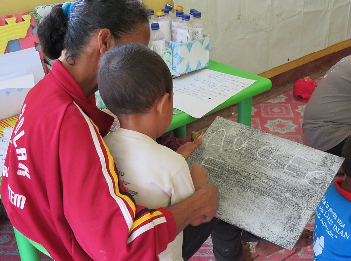Figure 6 Pre-school teacher helping a child with letter formation using ...